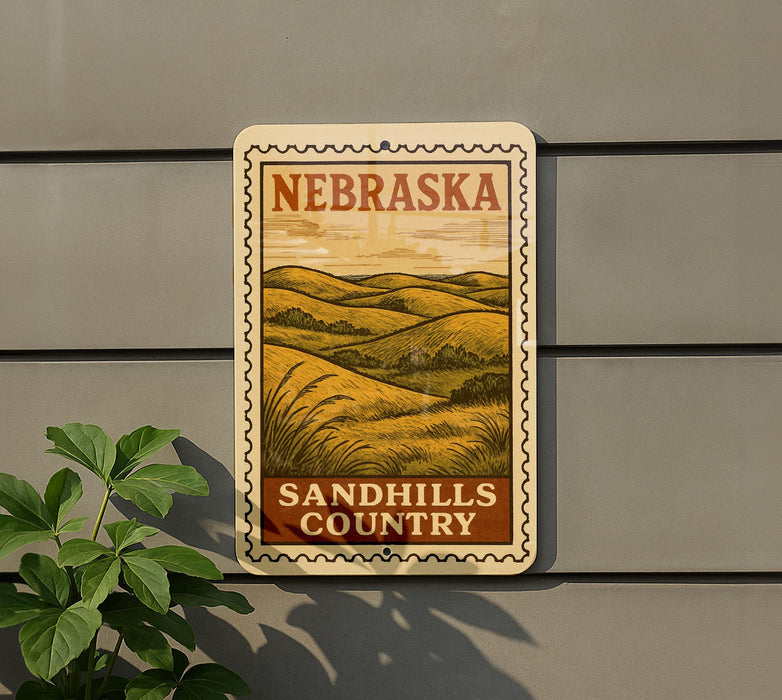 A metal sign with the text "NEBRASKA" and "SANDHILLS COUNTRY" is displayed on a gray wall, with a plant to the left of the sign.
