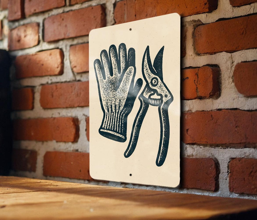 A sign with a pair of gardening gloves and pruning shears is displayed on a brick wall.