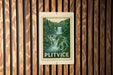 A postage stamp featuring a waterfall surrounded by lush greenery, mounted on a wooden wall.