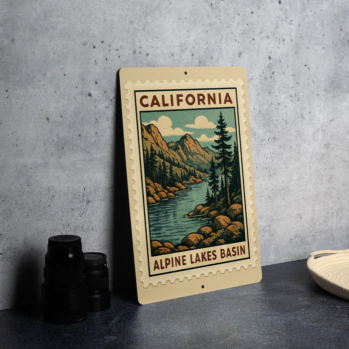A framed illustration of a scenic landscape with mountains, trees, and a river, depicting the Alpine Lakes basin in California.