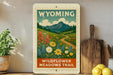 A framed poster of the Wildflower Meadows Trail in Wyoming, featuring a scenic landscape with mountains, a winding path, and colorful wildflowers.