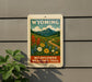A sign for the Wildflower Meadows Trail in Wyoming, featuring a scenic landscape with mountains, a winding path, and colorful wildflowers.