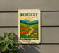 A sign for the Kentucky Wildflower Meadows Trail is displayed on a wall, featuring a vibrant illustration of a meadow with colorful wildflowers and a winding path.