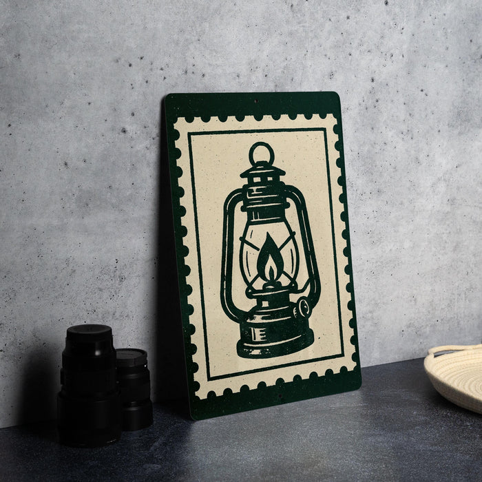 A framed image of a lantern is displayed on a table, accompanied by a stack of black camera lenses and a woven basket.