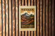 A Nevada postage stamp with a mountain landscape is displayed on a wooden wall.