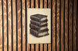 A metal sign with a stack of books on it is mounted on a wooden wall.