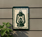 A green and white sign with a lantern illustration is mounted on a wall, next to a plant.