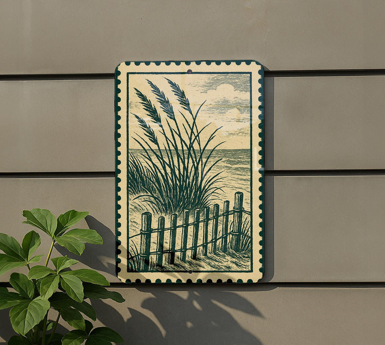 a framed artwork depicting a beach scene with a wooden fence and tall grasses, hanging on a wall next to a plant.