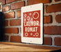 A sign with the text "Laundromat Romat" is hanging on a brick wall.