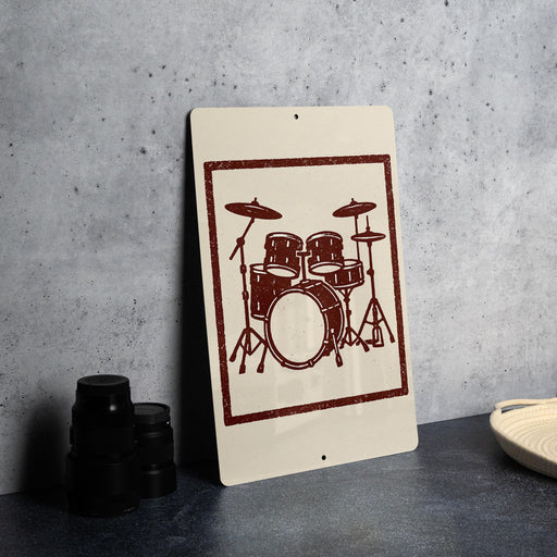 a sign with a drum set design on it, placed on a table next to some black camera lenses.