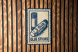A sign with the text "GLUE STICKS" is displayed on a wooden wall.