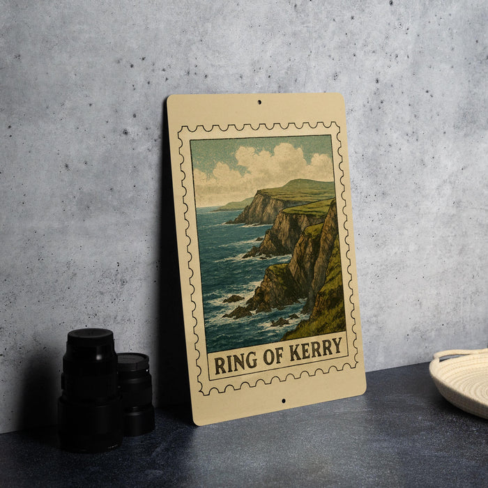 A framed illustration of the Ring of Kerry, a famous coastal region in Ireland, is displayed on a countertop next to some black camera lenses.
