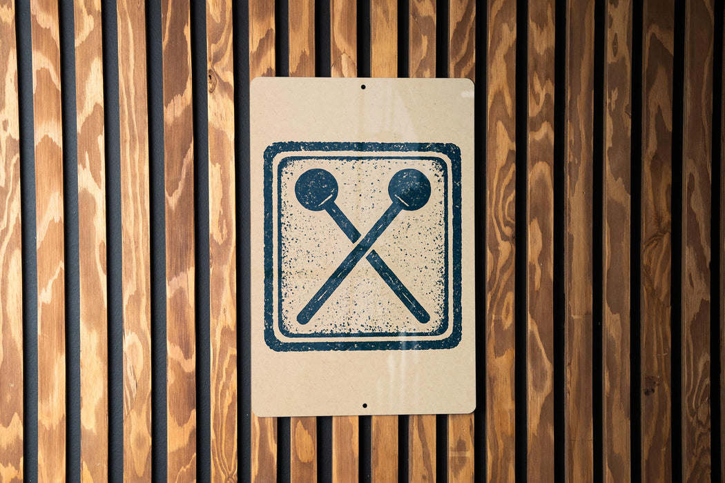 a sign with a symbol of two crossed drumsticks on a wooden background.