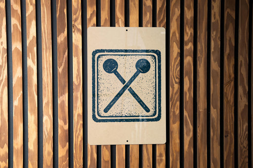a sign with a symbol of two crossed drumsticks on a wooden background.
