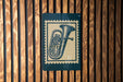 A blue and green metal sign with a musical instrument illustration is mounted on a wooden wall.