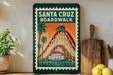 A vintage-style poster of the Santa Cruz Boardwalk roller coaster, featuring a large image of the roller coaster and palm trees, is displayed on a wall next to a wooden cutting board and a potted plant.