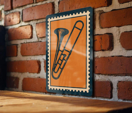 a trombone on a brick wall, with a small orange and blue stamp-like frame surrounding it.