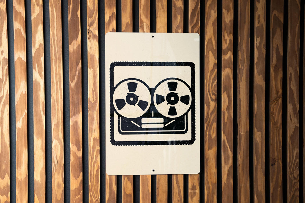 A sign with a stylized face and two circular objects is mounted on a wooden wall.
