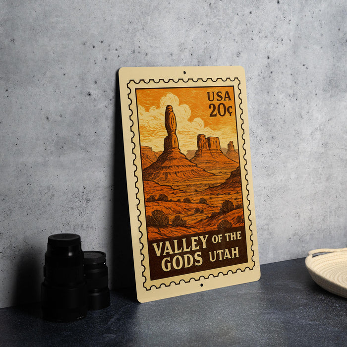 A metal sign with a desert landscape illustration, featuring mountains and a statue, is displayed on a table.