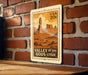 A vintage-style postage stamp depicting the Valley of the Gods in Utah, with a wooden surface in the foreground.