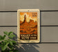 A framed postcard or stamp depicting the Valley of the Gods in Utah, with a desert landscape and a tall rock formation in the background.