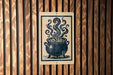 A sign with a black and white illustration of a pot with steam coming out of it, mounted on a wooden wall.
