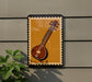 a framed illustration of a traditional Indian sitar, a stringed musical instrument, displayed on a wall.