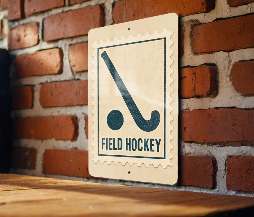 A sign with a hockey stick and the text "FIELD HOCKEY" is displayed on a brick wall.