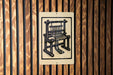 a sign with a black and white illustration of a wooden chair.