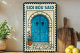 a decorative sign with a blue door and a plant, placed on a wooden surface next to a wooden cutting board and a potted plant.
