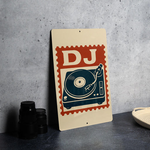 A metal sign with a stylized DJ turntable design and the letters "DJ" on it, placed on a gray surface next to some black camera lenses.