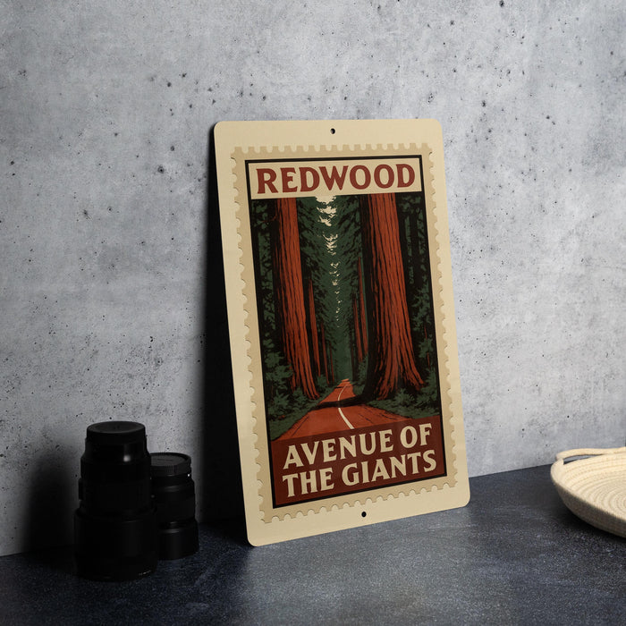 a vintage-style sign with the text "REDWOOD AVENUE OF THE GIANTS" and an illustration of a road leading through a forest of tall trees.