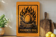 a sign with the text "PHOENIX EGG" and an illustration of a flaming egg, placed on a shelf next to a wooden cutting board and a potted plant.