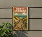 A vintage-style sign that reads "NORTH CAROLINA" is displayed on a wall, featuring a wooden boardwalk leading to a beach scene.
