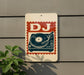 A sign with a stylized DJ turntable and the letters "DJ" is displayed on a wall, with a plant visible to the left.