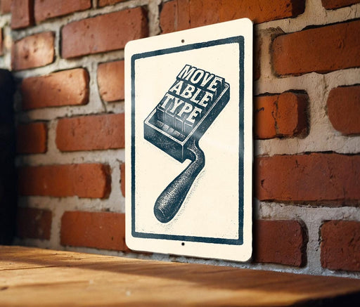 a sign with a graphic of a paintbrush and the text "MOVE ABLE TYP" on it, mounted on a brick wall.
