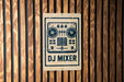 A sign for a DJ mixer is displayed on a wooden wall.