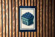 A blue and white illustration of a basket filled with blueberries is displayed on a wooden wall.