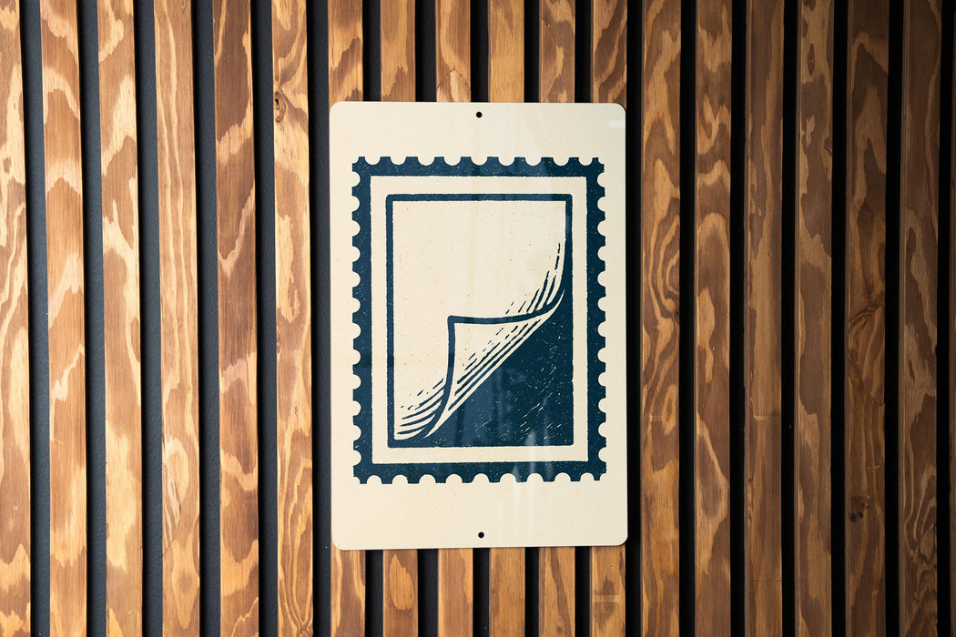 a white sign with a black stamp-like design on it, mounted on a wooden wall.