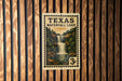 A Texas Waterfall Loop postage stamp is displayed on a wooden wall.