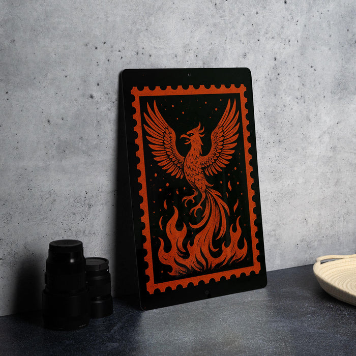 a framed artwork depicting a phoenix, a mythical bird, with flames and a fiery design on its wings. The artwork is displayed on a black surface, with a stack of black camera lenses and a white dish visible in the background.