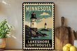 A vintage-style metal sign for the Minnesota Lakeshore Lighthouses, featuring a lighthouse and a rocky coastline with water.