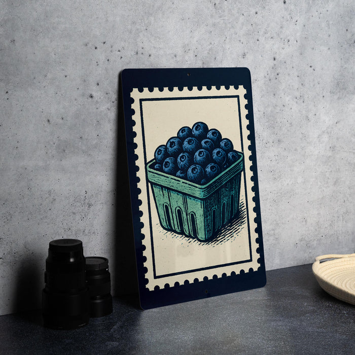 a framed illustration of a basket filled with blueberries, placed on a table next to some black camera lenses.