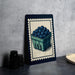 a framed illustration of a basket filled with blueberries, placed on a table next to some black camera lenses.