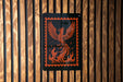 a black and orange graphic design on a wooden wall, depicting a phoenix with its wings spread wide.