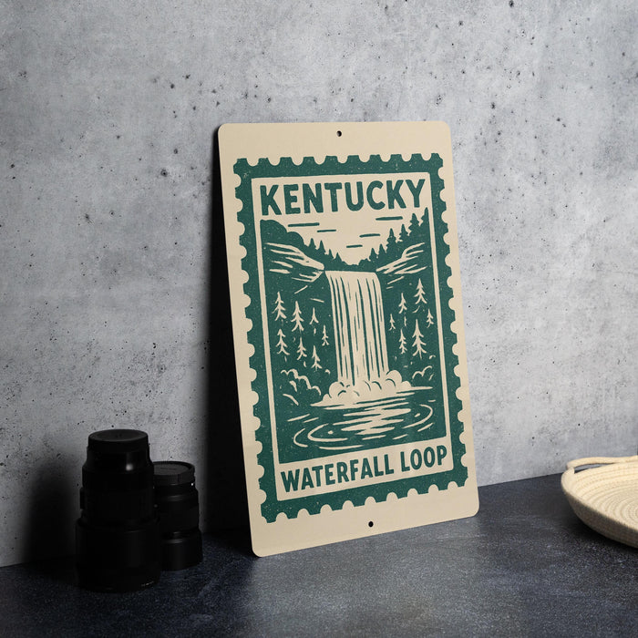 A sign for the Kentucky Waterfall Loop, featuring a waterfall and forest landscape, is displayed on a table next to some black camera lenses.