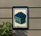 A sign featuring a blueberry basket on a wall, with a plant to the left.