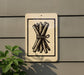 a sign with a black and white illustration of a bundle of sticks or branches, mounted on a wall.
