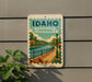 A sign for Idaho Riverwalk Promenade is displayed on a wall, featuring a scenic illustration of a riverwalk surrounded by trees and a lamppost.