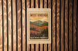 A metal sign with a vintage-style illustration of a mountainous landscape, mounted on a wooden wall.